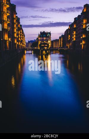 Blue hour in Warehouse District - Speicherstadt with lilac colored sky. Tourism landmark Wandrahmsfleet in twilight. Place is located in Port of Hambu Stock Photo