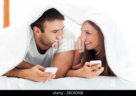Couple using smartphones in bed Stock Photo