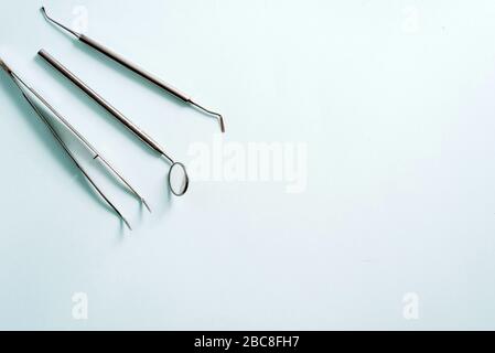 Dental tools on a blue background. Dental mirror and tweezers, dental treatment concept. Stock Photo