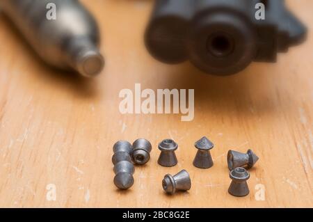 Airgun barrel muzzle, CO2 cartridge, pointed and hollow-point .177 airgun pellets.  The CO2 cartridge and gun muzzle are out of the depth of field. Stock Photo
