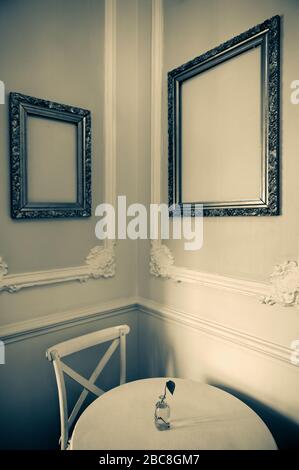 Mexico,Guanajuato State, Guanjuato, empty table and chair with empty art frames on the wall. Stock Photo