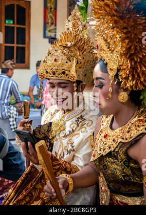 Vertical portrait of a bride and groom Facetiming at a Balinese wedding, Indonesia. Stock Photo