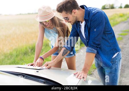 Couple reading a map while standing near convertible Stock Photo