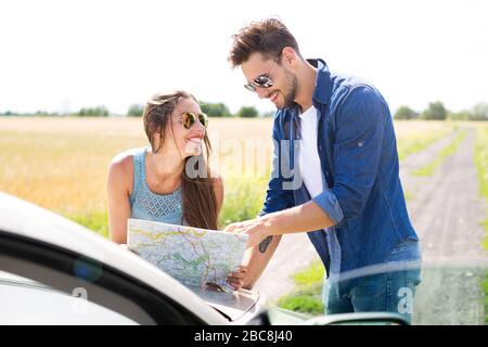 Couple reading a map while standing near convertible Stock Photo