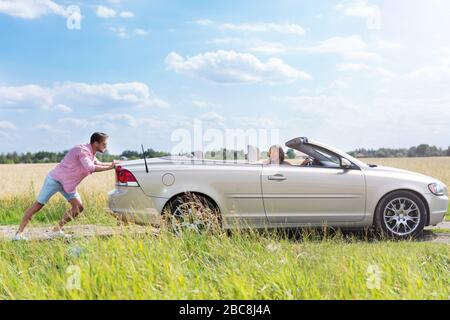 Man pushing broken down car Stock Photo