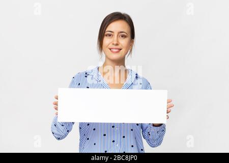 Happy brunette woman in elegant blue shirt showing white banner, isolated on white Stock Photo