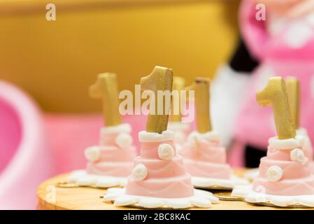 Sweet table decoration in children's party. Reception for birthday party. Decoration for girl anniversary party. Cupcakes with number one on top. Sele Stock Photo