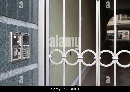 Built into the wall panel intercom with a gate and a prospect of the courtyard in the background with the arch. The concept of security of residential Stock Photo