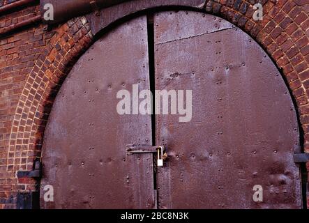 Architecture. Victorian brick railway arch. Rusty, padlocked door. Stock Photo