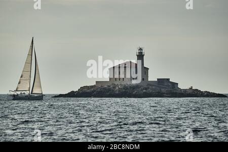 Sailboats compete in a sail regatta at sunset, race of sailboats, reflection of sails on water, multicolored spinnakers, number of boat is on aft Stock Photo