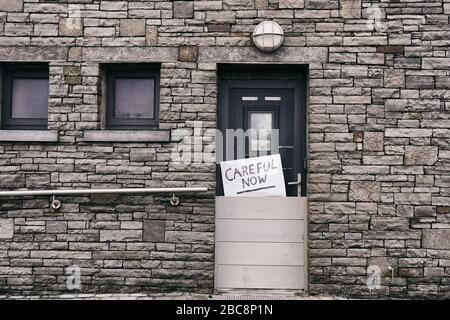 Careful now. A sign against a stoney wall. Stock Photo