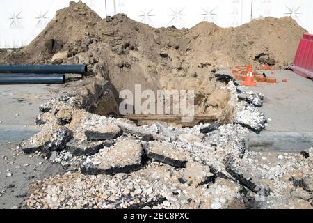 Laying a cold water sewer pipeline in the city asphalt. Background. Stock Photo
