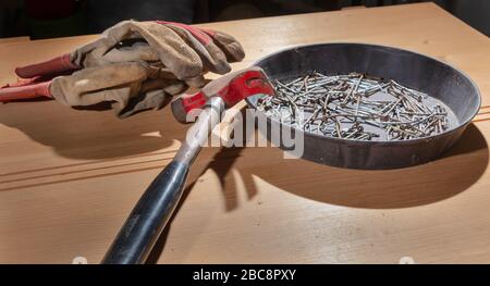 old rusty hammer and construction gloves laid on wooden board in studio Stock Photo