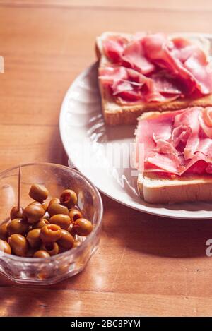 Green olives and toast with serrano ham, traditional spanish snack Stock Photo