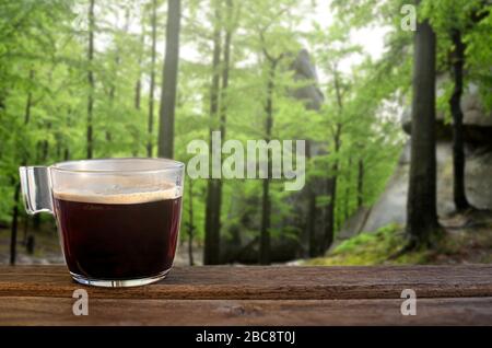 Cup of black coffee on wooden table with view of the green forest, tree and natural view background Stock Photo
