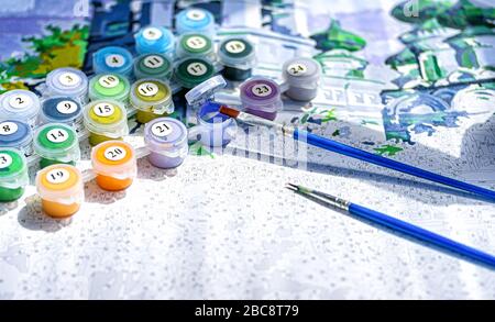 Painting by numbers. Set to paint the picture, includes a canvas, paints of different colors, brushes. Selective focus. Close up. Stock Photo