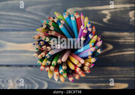colored pencils in a pencil cup on wooden table, close up photo, view from above Stock Photo