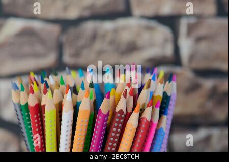colored pencils, close up photo in front of a blurred wall background Stock Photo
