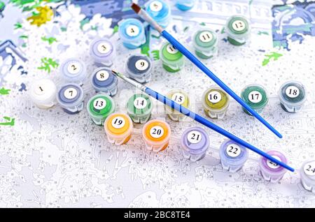Painting by numbers. Set to paint the picture, includes a canvas, paints of different colors, brushes. Selective focus. Close up. Stock Photo