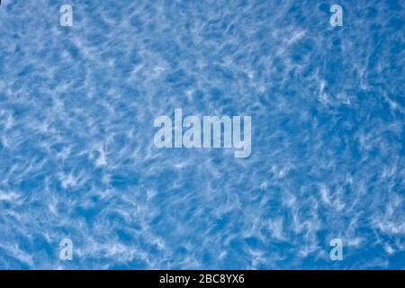 Curly white cirrus clouds on deep  blue sky, empty space for text or banner. Stock Photo