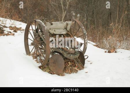 Vintage 100 year old potato planter sits idle on a snowy field in Massachusetts. Stock Photo