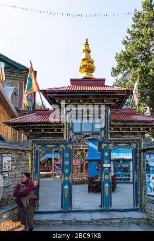 Nepalese woman in front of the entrance gate of Namrung (2630 m) Stock Photo