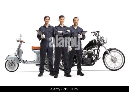 Full length portrait of motorcycle mechanic workers in uniforms posing next to motorbikes isolated on white background Stock Photo