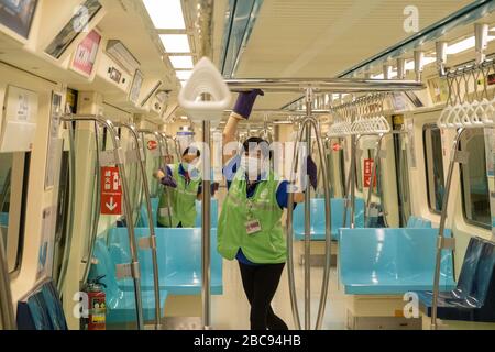 Metro staff wearing protective masks and gloves clean and disinfect a tram as a preventive measure against the spread of Coronavirus.Taiwan had a surge of COVID-19 cases in the last days, bringing the total number to 348. The government released new rules of social distancing and made the wearing of masks compulsory on public transportations. Stock Photo