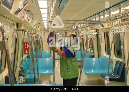 A Metro staff wearing a protective mask and gloves cleans and disinfects a tram as a preventive measure against the spread of Coronavirus.Taiwan had a surge of COVID-19 cases in the last days, bringing the total number to 348. The government released new rules of social distancing and made the wearing of masks compulsory on public transportations. Stock Photo