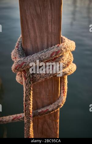 Sunrise photo with golden glow of Rope at dock on river waiting for boat to be docked. Stock Photo
