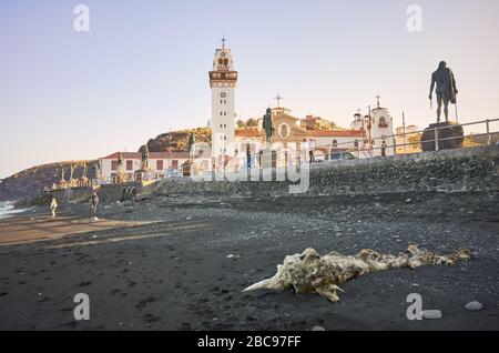 Candelaria, Tenerife, Spain - May 01, 2019: The Basilica of the Royal Marian Shrine of Our Lady of Candelaria  seen from volcanic beach at sunset. It Stock Photo