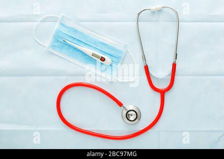 Medical mask thermometer red stethoscope, Surgical protection face mask on blue background. Doctors professional equipment. Healthcare medical concept Stock Photo