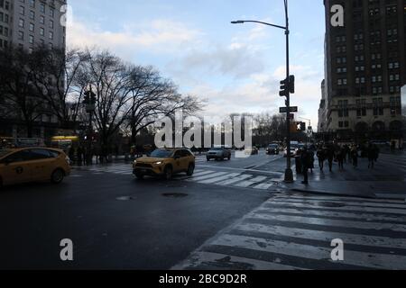 New York yellow taxi on a gloomy, rainy day at the intersection of 5th Avenue and West 58th St. Midtown Manhattan with Central Park in the background Stock Photo