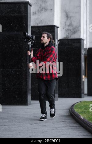 Young Professional videographer holding professional camera on 3-axis gimbal stabilizer. Pro equipment helps to make high quality video without Stock Photo