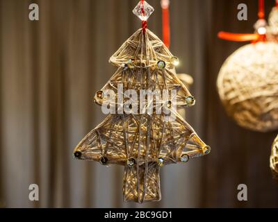 Tinted photo of New Year's handmade jewelry made of threads in the form of Christmas tree decorated with sequins Stock Photo