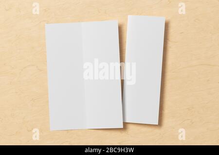 Blank vertical A4 leaflet on wooden background. Bi-fold or half-fold opened and folded brochure isolated with clipping path. View directly above. 3d i Stock Photo