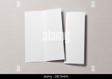 Blank vertical A4 leaflet on white wooden background. Bi-fold or half-fold opened and folded brochure isolated with clipping path. Side view. 3d illus Stock Photo