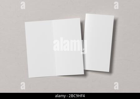 Blank square leaflet on white wooden background. Bi-fold or half-fold opened and folded brochure isolated with clipping path. View directly above. 3d Stock Photo