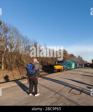 Rail enthusiast / train-spotter taking a photograph of a Direct Rail Services class 68 locomotive on a railway station Stock Photo