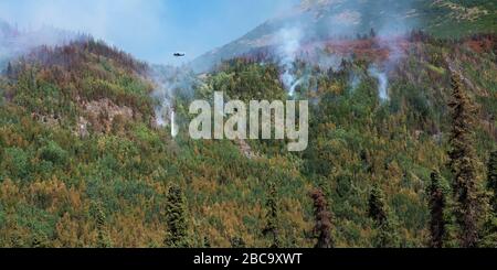 helicopter dropping water on smoke on hillside Stock Photo