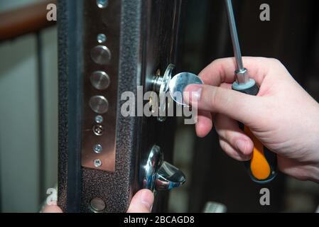 A man repairs a door lock. Close-up. Stock Photo