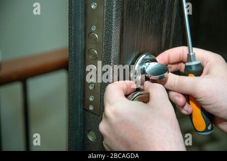 A man repairs a door lock. Close-up. Stock Photo