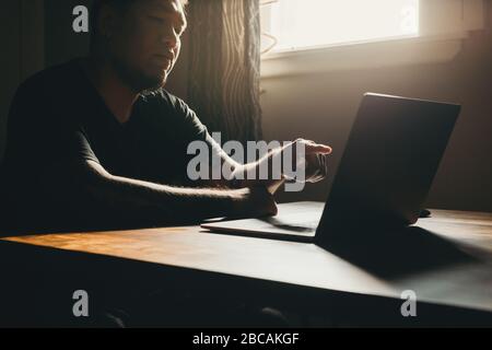 A asian man working  on laptop in dark area. Pointing to the screen. Stock Photo