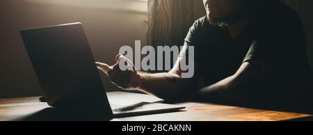 A asian man working  on laptop in dark area. Pointing to the screen. Stock Photo