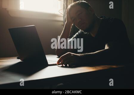 A asian man working  on laptop in dark area. Sadness gesture. Stock Photo