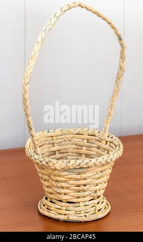A wooden basket with a large handle stands on a wooden table close-up. Stock Photo