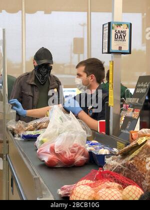 (200404) -- DALLAS, April 4, 2020 (Xinhua) -- A store cashier wearing a mask helps a customer who wears a scarf inside Aldi supermarket in Plano, a suburban city of Dallas, Texas, the United States, on April 3, 2020. U.S. President Donald Trump said on Friday the Centers for Disease Control and Prevention (CDC) now recommends that Americans wear cloth face coverings to protect against COVID-19. 'The CDC is advising the use of non-medical cloth face covering as a voluntary health measure,' Trump told a White House briefing. 'It is voluntary. They suggested for a period of time.' (Photo by D Stock Photo