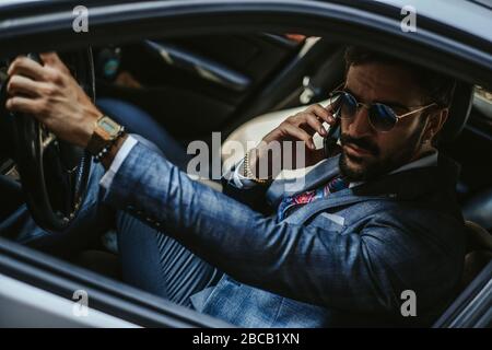 Serious entrepreneur driving the car and talking on the mobile phone Stock Photo