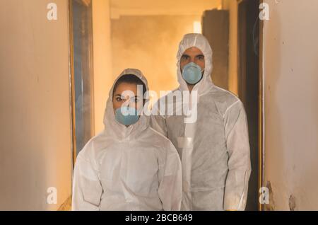 Couple of virologist doctors and scientists wearing biohazard insulation suits inspecting an infected house during a virus outbreak pandemic Stock Photo