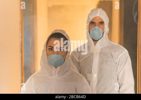 Couple of virologist doctors and scientists wearing biohazard insulation suits inspecting an infected house during a virus outbreak pandemic Stock Photo